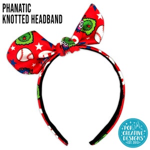 May include: Red knotted headband with a baseball and monster print. The headband is tied in a bow and has a black elastic band.