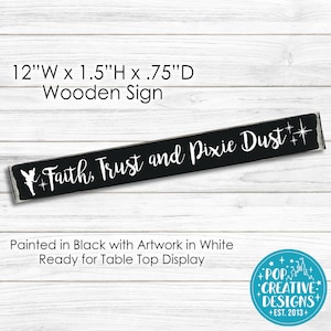 May include: Black wooden sign with white lettering that reads "Faith, Trust and Pixie Dust" with a fairy silhouette and stars. The sign is 12 inches wide, 1.5 inches high, and 0.75 inches deep.