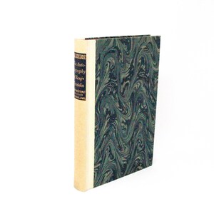 May include: A hardcover book titled The Autobiography of Benjamin Franklin with a cream-colored spine and a dark green and black marbled cover pattern. The spine features gold lettering and decorative borders on a dark blue rectangular label.