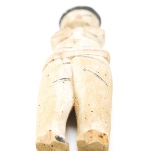 以下が含まれることがあります： 黒の帽子をかぶった人の木製の置物で、白と黒で塗られています。置物は腕を組んで立っており、シンプルなデザインです。