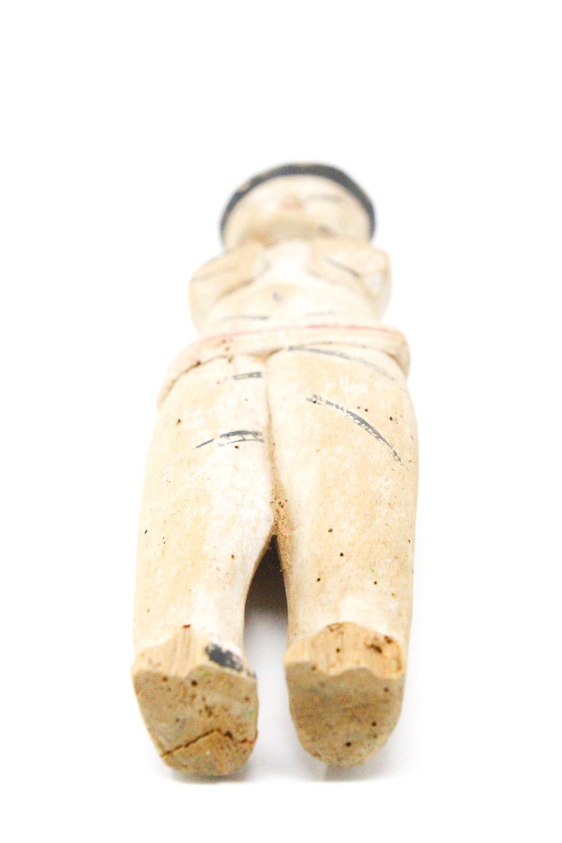 以下が含まれることがあります： 黒の帽子をかぶった人の木製の置物で、白と黒で塗られています。置物は腕を組んで立っており、シンプルなデザインです。