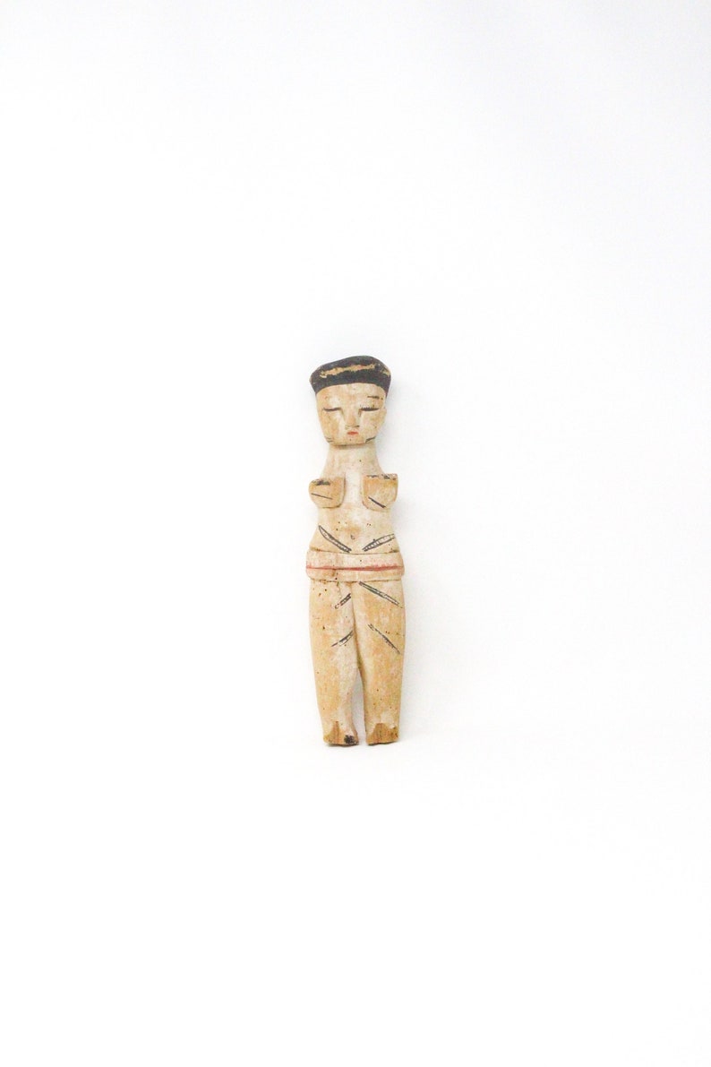 以下が含まれることがあります： 黒の帽子をかぶった人の小さな木製の置物で、白、赤、黒で塗られています。置物は腕を組んで立っています。