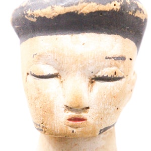 以下が含まれることがあります： 閉じた目、塗られた鼻と口、そして黒く塗られた髪の毛を持つ木製のドールヘッド