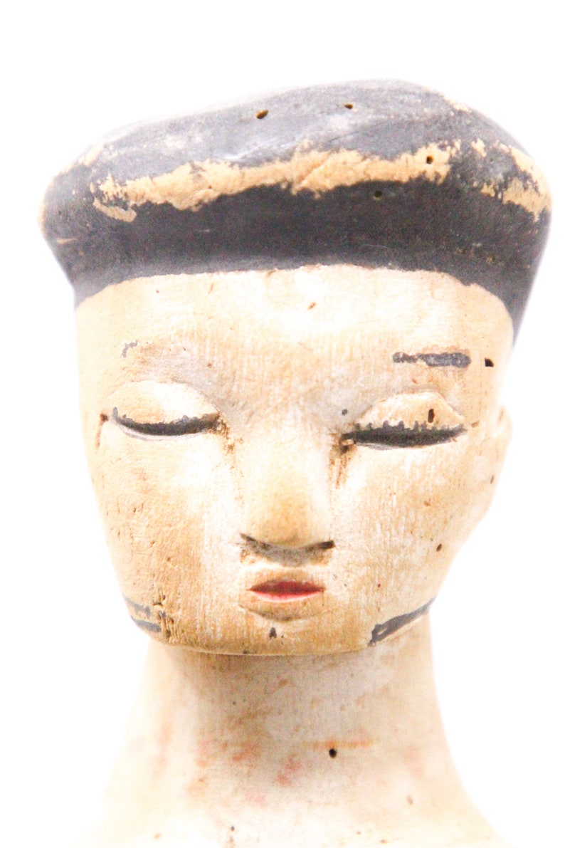 以下が含まれることがあります： 閉じた目、塗られた鼻と口、そして黒く塗られた髪の毛を持つ木製のドールヘッド