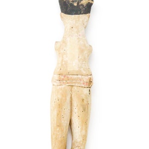 以下が含まれることがあります： 人の小さな木製の置物。置物は薄い茶色に塗られており、黒い帽子をかぶっています。置物は腕を体の横につけた状態で立っています。