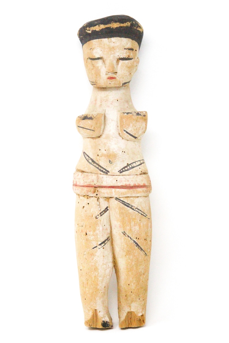 以下が含まれることがあります： 黒の帽子をかぶった人の木製の置物で、黒、白、赤で塗られています。置物は腕を伸ばして立っており、体にスタイリッシュなデザインが施されています。