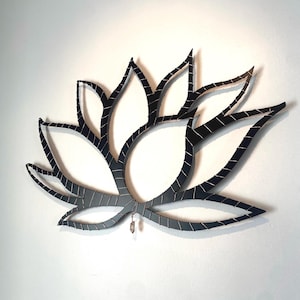 Può includere: Arte da parete in metallo nero a forma di fiore di loto. Il fiore è realizzato con sottili strisce di metallo intrecciate. Il fiore ha un design delicato e intricato.