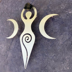Può includere: Un decoro da parete in metallo dorato con una figura femminile stilizzata con un motivo a spirale e tre lune crescenti.