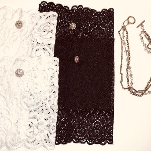 May include: Two pairs of lace wrist cuffs, one white and one black, with jeweled embellishments. A silver chain bracelet with crystal accents.