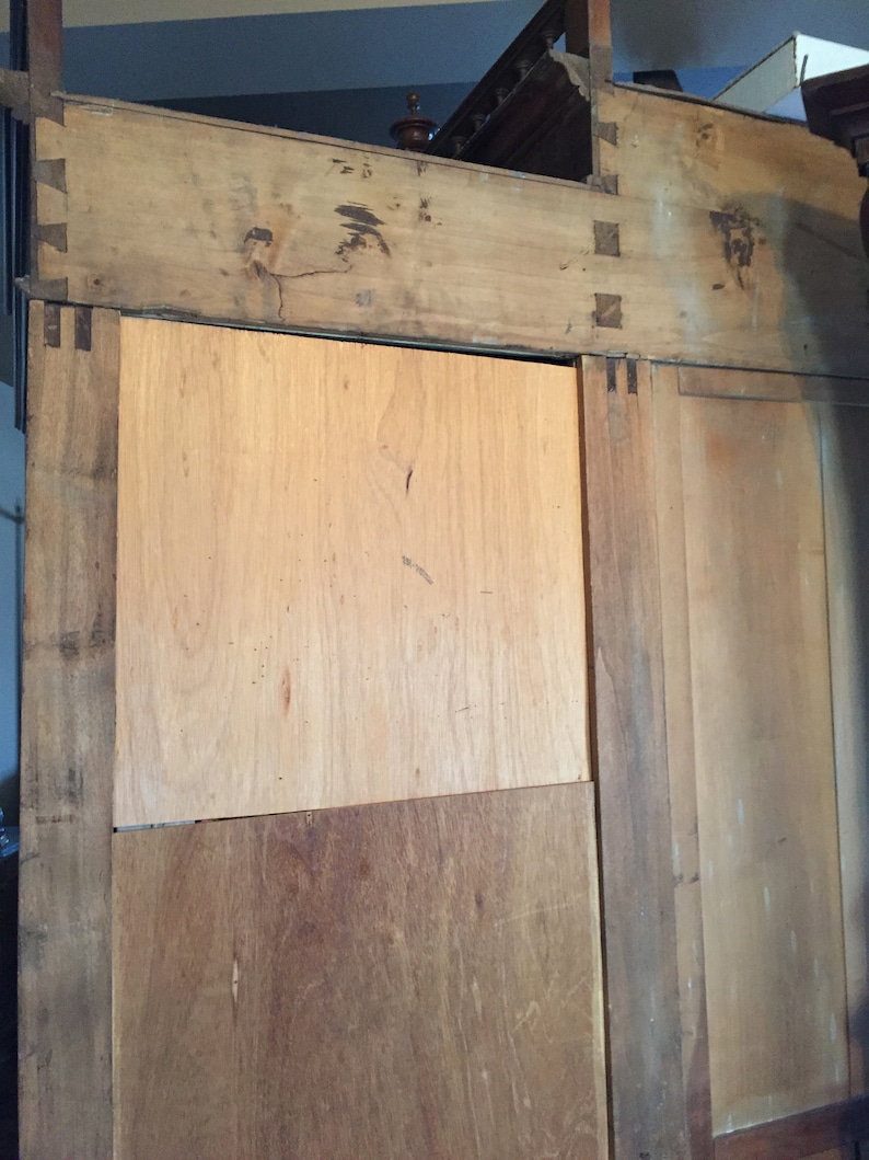 May include: A wooden cabinet with two doors and a shelf. The cabinet is made of light brown wood and has a simple design.