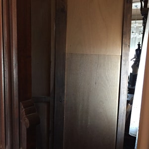 May include: A wooden cabinet with a dark brown finish and a single door. The door is closed and has a simple design. The cabinet is made of wood and has a traditional style.