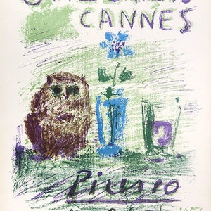 Op de afbeelding: Een vintage kunstposter voor Galerie 65 Cannes met een Picasso-kunstwerk. De poster heeft een groen en paars kleurenschema met een uil, een vaas met bloemen en een glas. De tekst bevat "Picasso" en data.