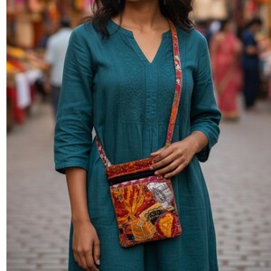 K&ouml;nnte beinhalten: Ein t&uuml;rkisfarbenes Kleid mit V-Ausschnitt und Dreiviertel&auml;rmeln. Eine bunte Patchwork-Umh&auml;ngetasche mit rotem Riemen wird quer &uuml;ber dem K&ouml;rper getragen. Die Tasche hat eine Vielzahl von Mustern und Farben, darunter Orange, Gelb und Rot.