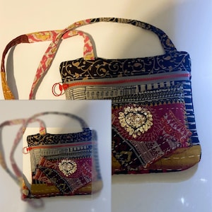 May include: A patchwork shoulder bag with a patterned strap and a zipper closure. The bag features a mix of fabrics in black, red, and gold, with a heart-shaped sequin embellishment. The bag has a small handle and a long strap.