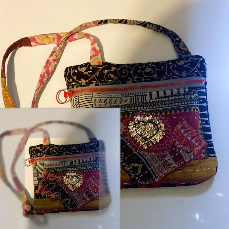 May include: A patchwork shoulder bag with a patterned strap and a zipper closure. The bag features a mix of fabrics in black, red, and gold, with a heart-shaped sequin embellishment. The bag has a small handle and a long strap.