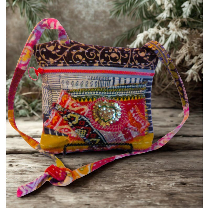 May include: A colorful patchwork crossbody bag with a patterned strap. The bag features a mix of fabrics in various colors, including red, yellow, blue, and brown. A large sequined embellishment is centered on the front. The bag has a zipper closure.