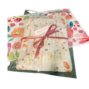 May include: A gift wrapped in floral patterned tissue paper, tied with a pink ribbon. The tissue paper features a delicate design of wildflowers in shades of orange, pink, and purple. A small tag reads "thank you for your order."
