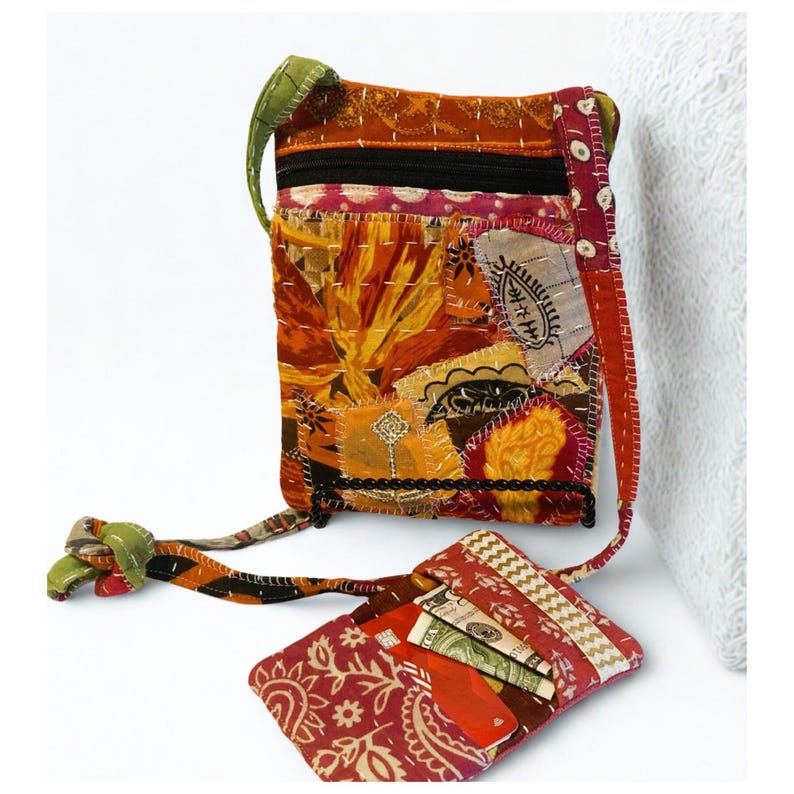 K&ouml;nnte beinhalten: Eine Patchwork-Umh&auml;ngetasche und eine passende Geldb&ouml;rse. Die Tasche hat Stoffflicken in Orange, Rot und Gelb, mit einem schwarzen Rei&szlig;verschluss und gr&uuml;nen Riemendetails. Die Geldb&ouml;rse zeigt ein rotes Paisley-Muster.