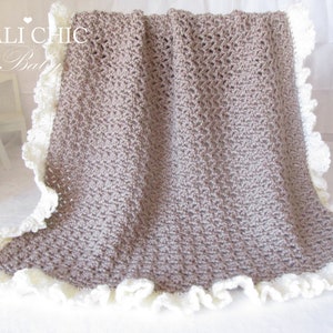 May include: A brown crocheted baby blanket with a white crocheted lace trim. The blanket is folded in half and has a "Cali Chic Baby" label in the top left corner.