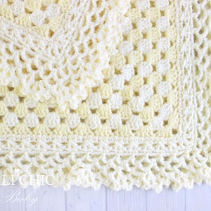 May include: A crocheted baby blanket in shades of white and yellow with a scalloped edge.