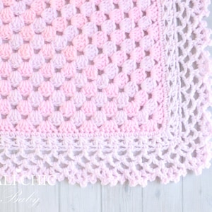 May include: A pink and white crocheted baby blanket with a delicate scalloped edge.