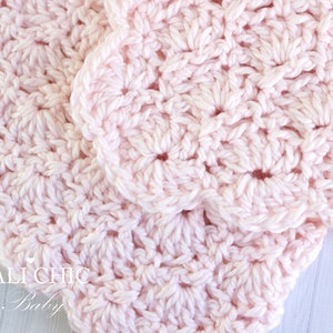 May include: A close-up of a pink crocheted baby blanket with a delicate, lacy pattern. The blanket is made with soft yarn and has a gentle, feminine feel.