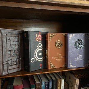 The Neverending Story special illustrated edition, on bookshelf from left, Chronicles of Narnia (leather wardrobe), The Lord of the Rings (black leather, Neverending Story, and the Last Unicorn(light purple leather)