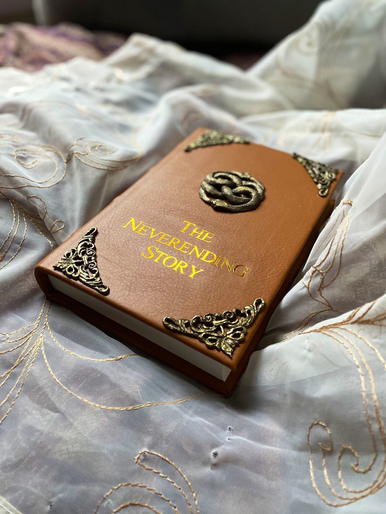 The Neverending Story book, leather bound, gold title, aged gold filigree corner pieces and ouroboros, two snakes entwined to create the "Auryn".