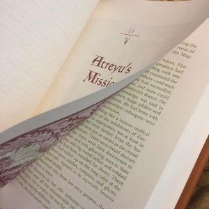 Photo showing the inside of The Neverending Story book, flipping through the pages, showing the red and green text, and how the chapter begins with an illustrated letter/