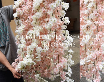 May include: A long garland of pink and white artificial cherry blossoms. The garland is made of plastic and has a realistic look. The garland is labeled "Great Harvest of Cherry Blossoms".