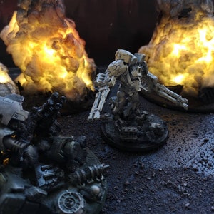 May include: A white miniature robot figure with a gun, standing on a black base. The robot is surrounded by three miniature explosions, each with a bright yellow glow.