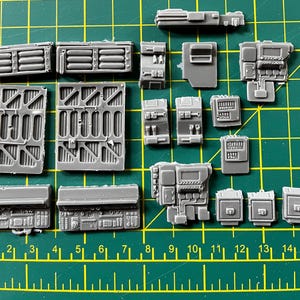 May include: A set of 16 grey plastic model pieces for a spaceship or other sci-fi vehicle. The pieces are various shapes and sizes, including panels, doors, and windows.