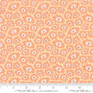 May include: Peach-colored fabric with a repeating pattern of small white flowers. The fabric is measured with a ruler that reads "moda" at the 2-inch and 6-inch marks.