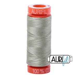 May include: A spool of Aurifil 100% cotton thread in a light gray color. The spool is labeled "Aurifil 100% Cotton" and has a red and white label.