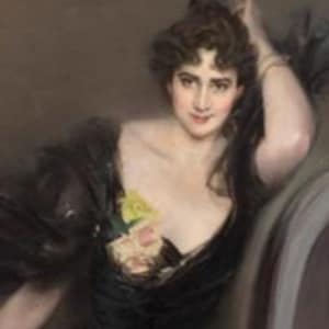 May include: A woman in a black gown with a low neckline, sitting in a chair. She is wearing a pearl necklace and a bracelet. She has dark hair and is looking at the viewer. The background is a light brown.