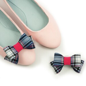 Könnte beinhalten: Ein Paar rosa Ballerinas mit einem karierten Schleifenband an jedem Schuh. Ein kleineres kariertes Schleifenband ist ebenfalls enthalten.