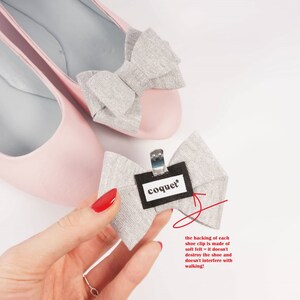 Pode incluir: Um par de sapatilhas de bal&eacute; cor-de-rosa com la&ccedil;os de glitter prata. O la&ccedil;o do sapato direito &eacute; preso com um clipe de feltro que diz "coquet".