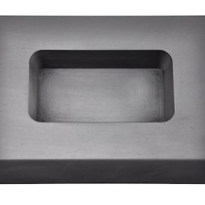 May include: A grey rectangular graphite mould for casting metal. The mould has a rectangular cavity in the centre.