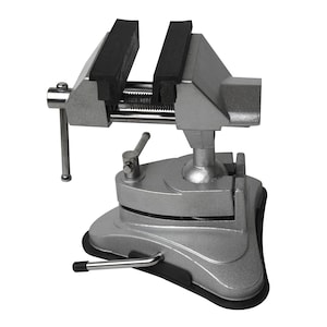 May include: A silver bench vise with black rubber jaw protectors. The vise has a swivel base and a handle for tightening. It is designed for holding objects securely during various tasks.