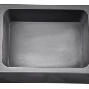 以下が含まれることがあります： 角が丸い長方形の濃い灰色のるつぼ。内部は滑らかでくぼんだ盆地です。るつぼは金属を溶かすように設計されており、耐熱性の材料で作られています。