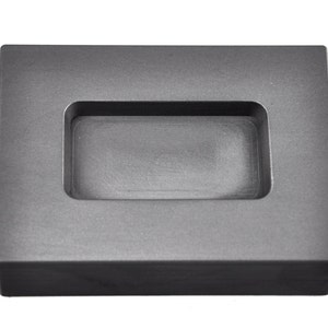 May include: A gray rectangular mold with a rectangular recess in the center. The mold is made of a material that appears to be graphite or ceramic.