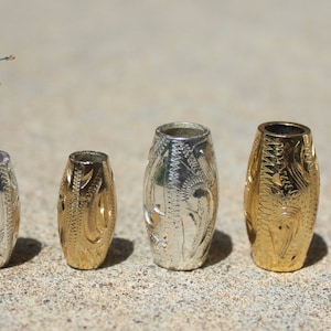 May include: A set of six silver and gold metal beads with an intricate engraved design. The beads are oval shaped and range in size.  Leads Leather.