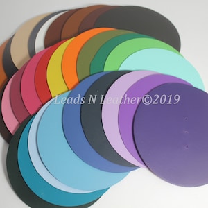 May include: A variety of leather circles in different colors, including brown, red, orange, green, blue, purple, and white. The circles are arranged in a fan shape, with the largest circle at the bottom and the smallest circle at the top. The text "Leads N Leather©2019" is visible in the center of the image.