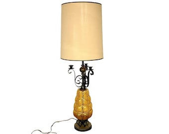 May include: A vintage table lamp with a black metal base and a yellow glass shade. The base features a candelabra design with five arms. The lamp has a beige fabric shade.