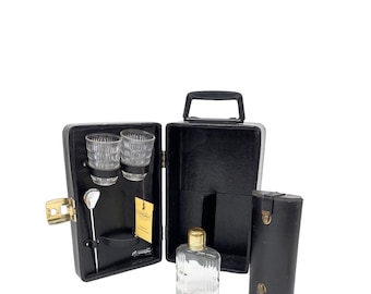 May include: Black leather travel bar set with two shot glasses, a stirrer, and a small bottle. The set is open and the bottle is visible.