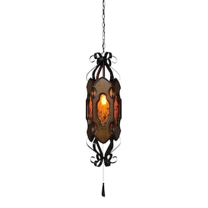 May include: A vintage hanging lantern with a dark wood frame and amber-colored glass panels. The lantern is suspended by a chain and features decorative black metal accents, including bow-shaped details. A tassel hangs from the bottom.