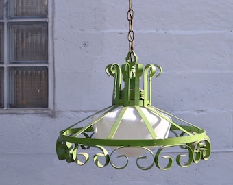 May include: A green metal chandelier with a white glass shade. The chandelier has a decorative, scrolled design and hangs from a chain.