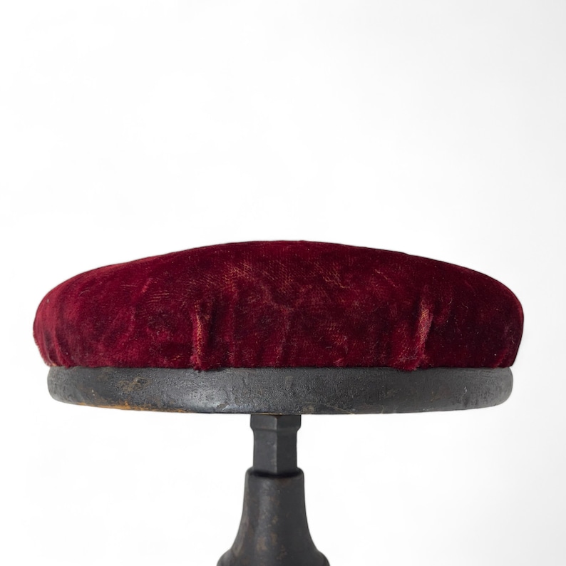 Vintage goth Spanish Revival adjustable stool with cast iron base and a red velvet round seat.