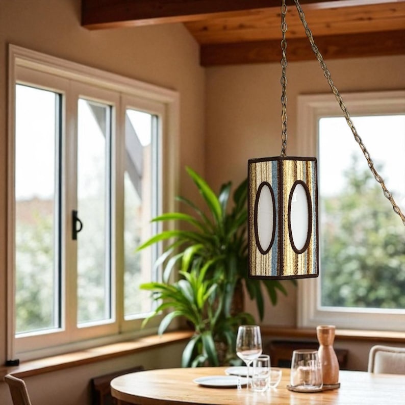 Vintage cottagecore swag lamp with hexagonal shape and oval cutout, hanging on chain from the ceiling in a country breakfast nook.