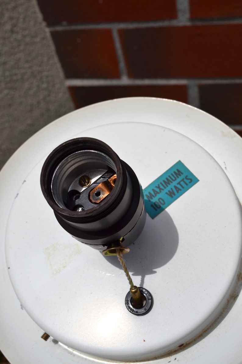 May include: A white ceiling fixture with a black electrical socket and a blue label that reads "MAXIMUM 100 WATTS".